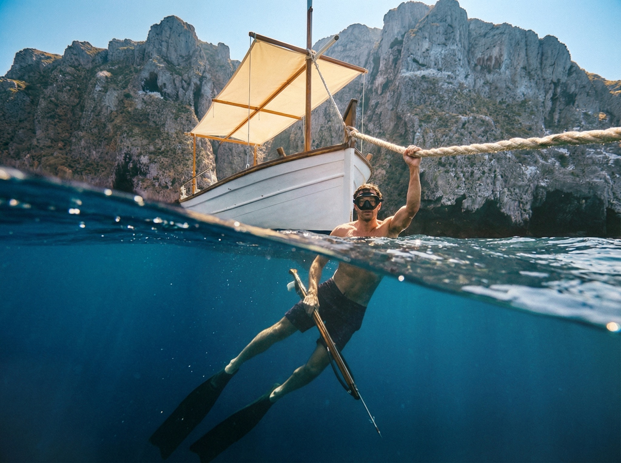 Diver beneath a sailboat, seen above and below the waterline