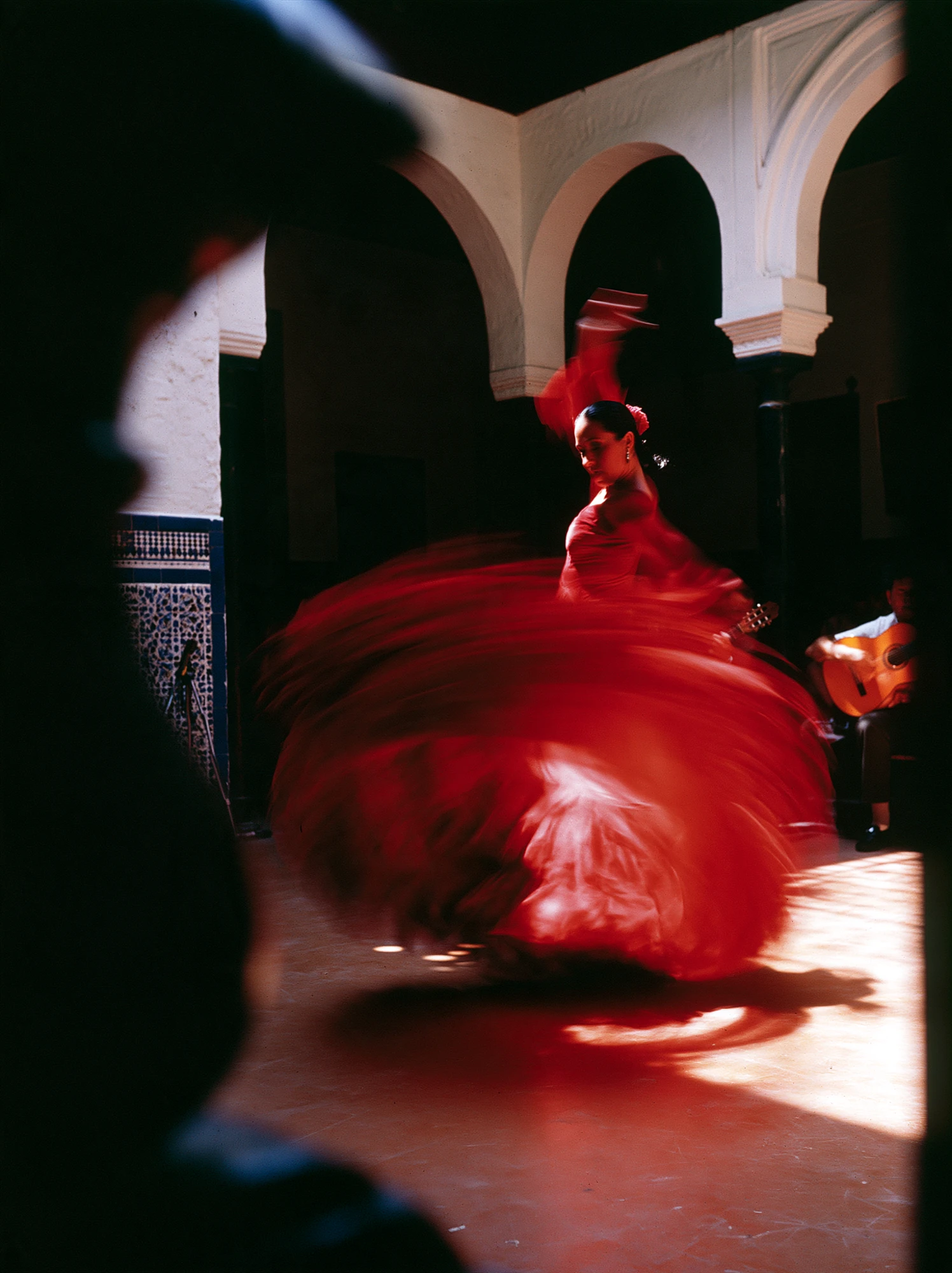 Red flamenco dress moving through an Andalusian courtyard